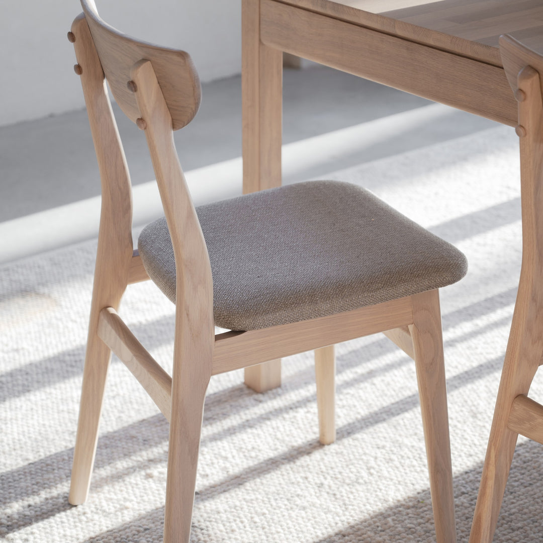 Rowico Rodham spisestol i hvitpigmentert eik med gråbeige sete ved lyst eikebord, stripet teppe i sollys