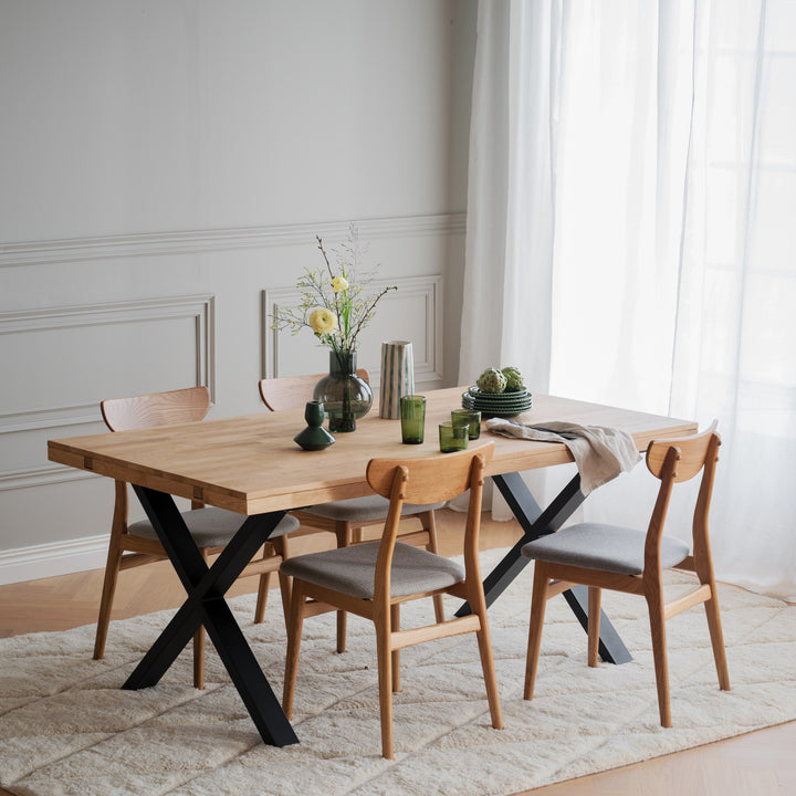 Rowico Rodham spisestoler i eik med gråbeige sete rundt eikebord med sorte kryssben, panelvegg og blomster