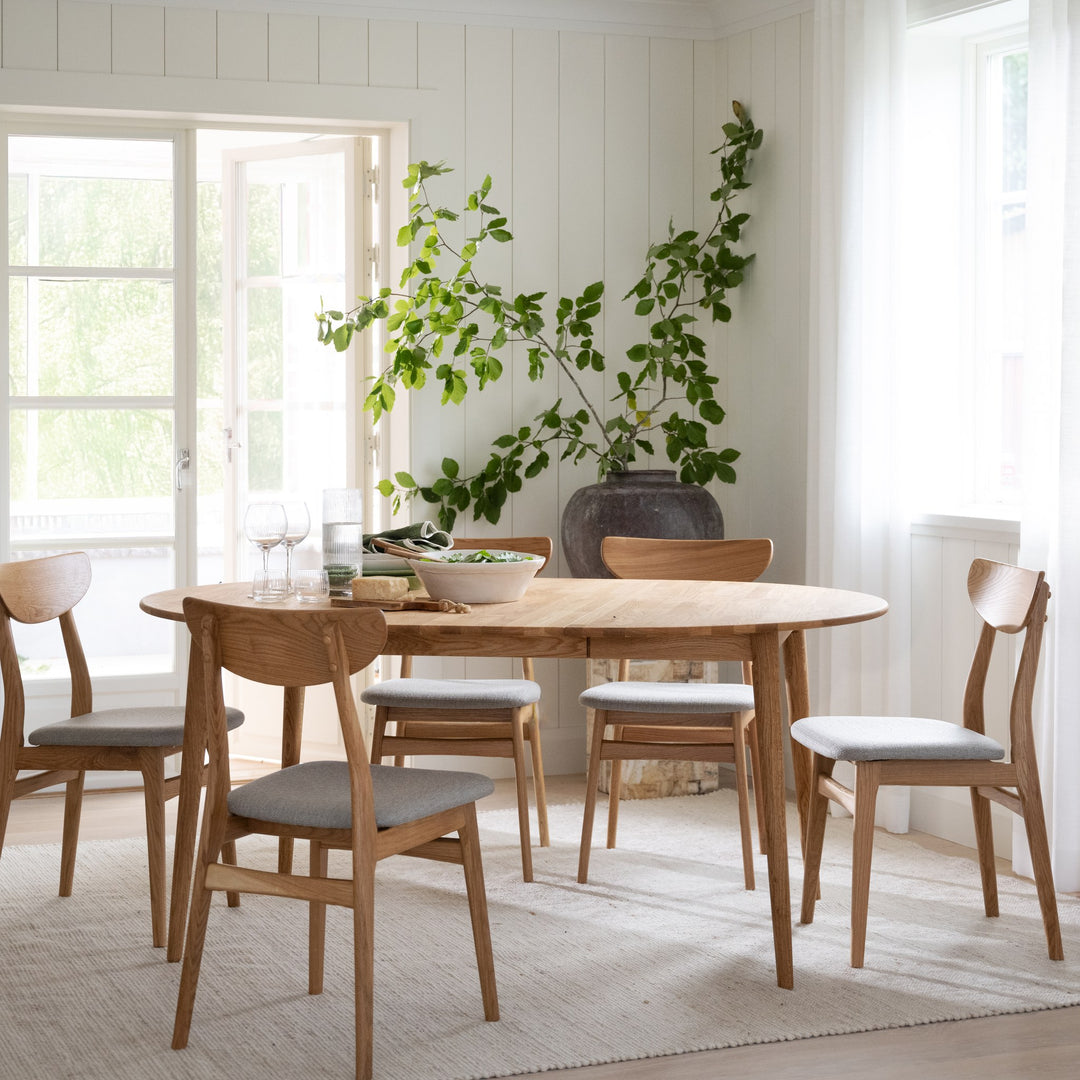 Rowico Rodham spisestoler i eik med gråbeige sete ved rundt eikebord i lyst rom med grønn plante i mørk vase