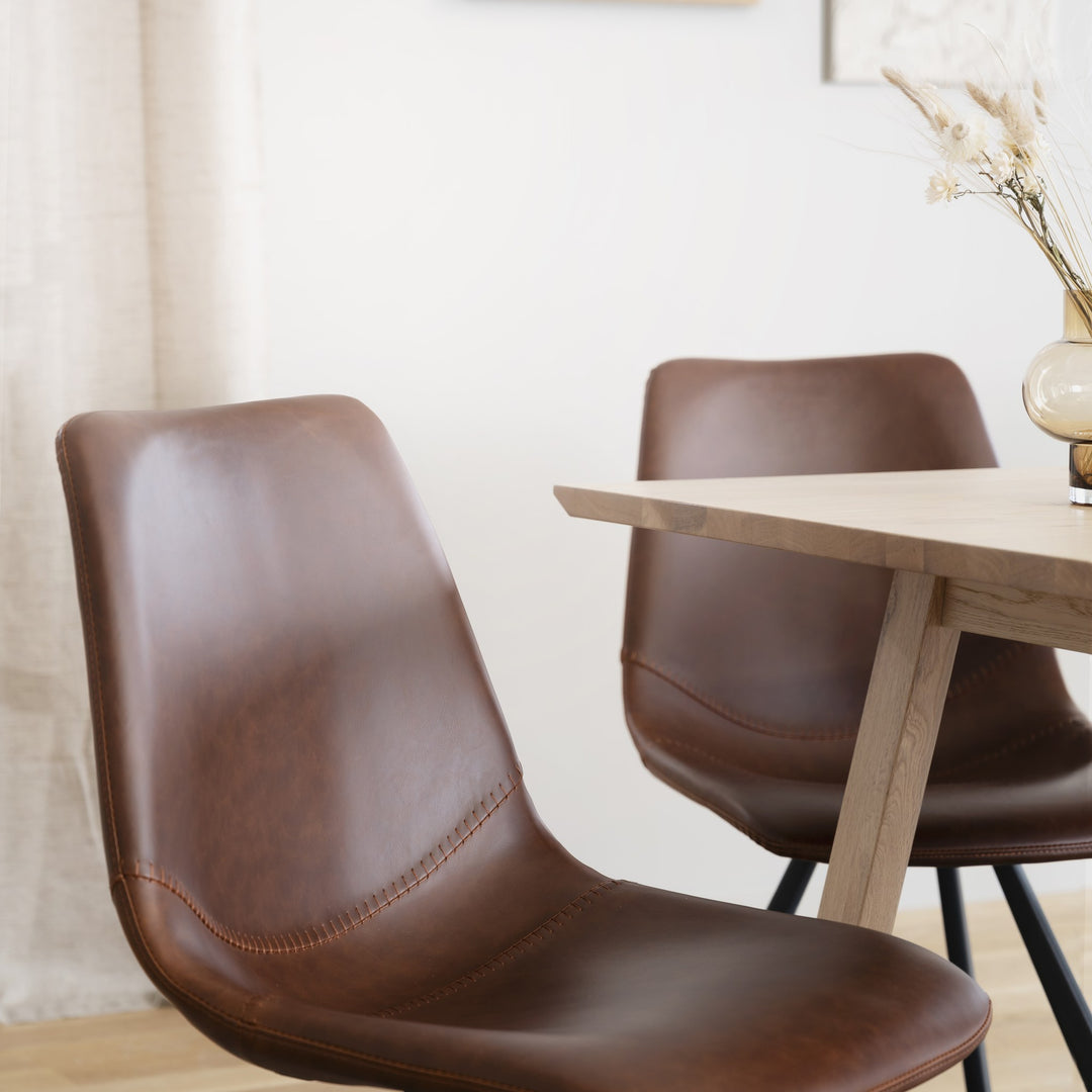 Rowico Auburn spisestol i brunt kunstskinn ved lyst eikebord i lyst rom med tørket pampasgress