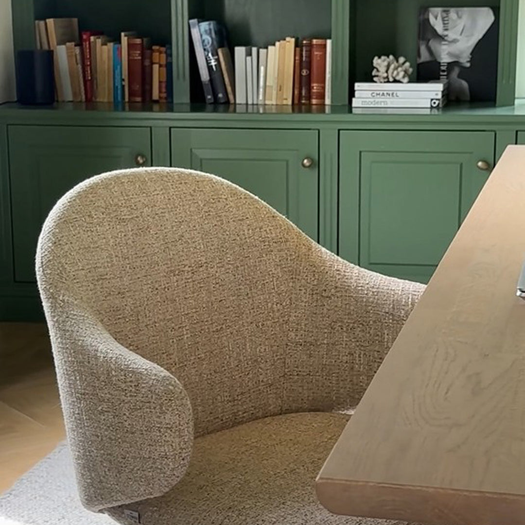 Rowico Drake spisestol i beige bouclé ved lyst trebord foran grønt bokskap