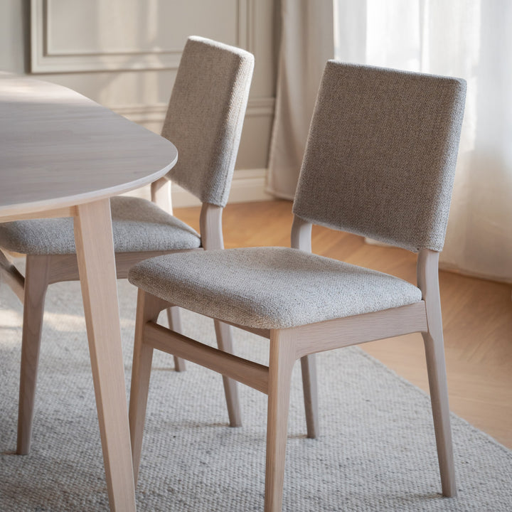 Rowico Medford spisestol i lys eik med beige bouclésete og -rygg ved ovalt bord