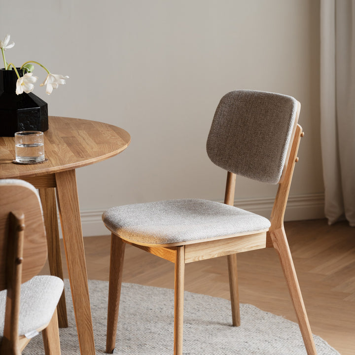 Rowico Barrett spisestol i gråbeige bouclé med lyse eikeben ved eikebord med tulipaner