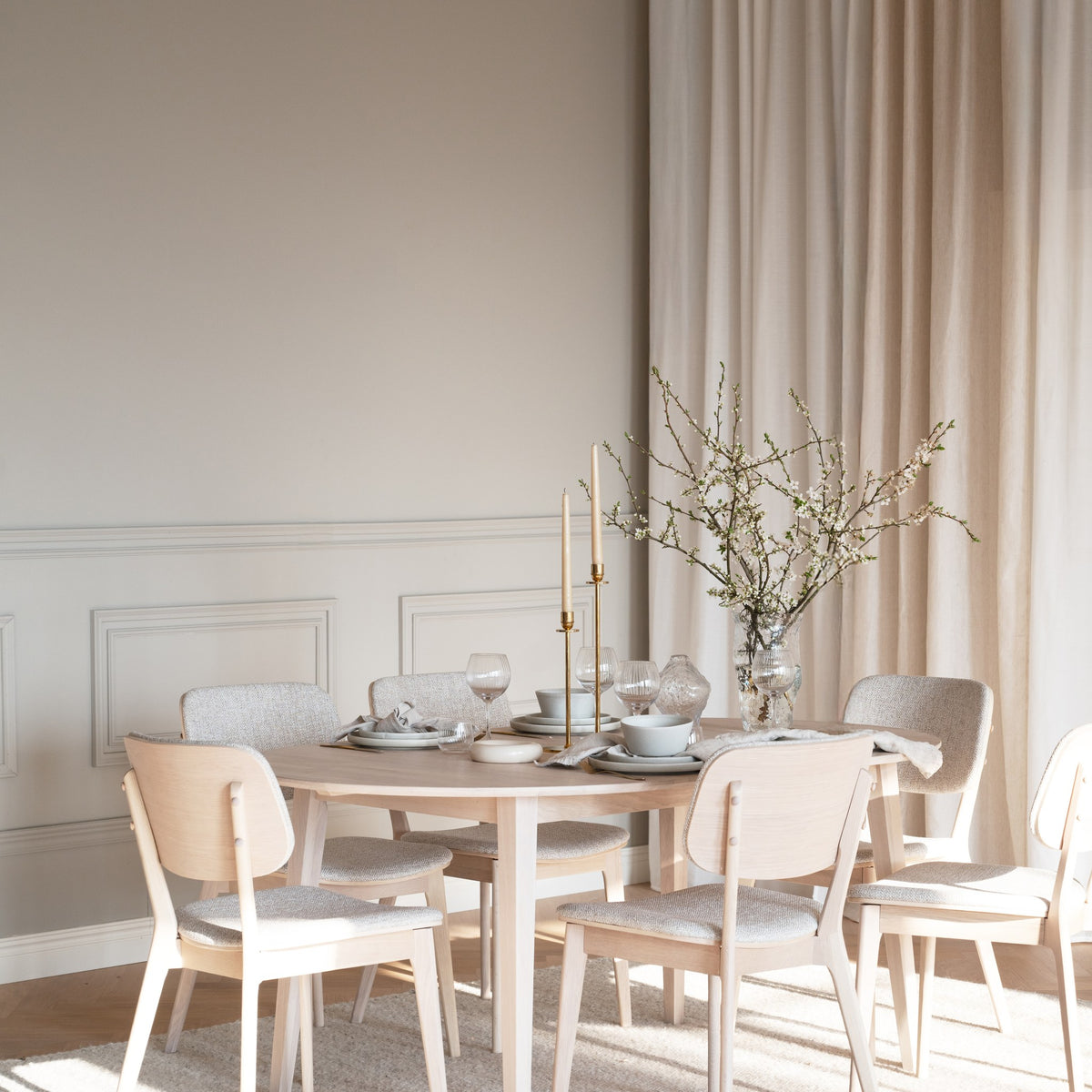 Rowico Barrett spisestoler i lyst stoff rundt hvitpigmentert eikebord i elegant spisestue