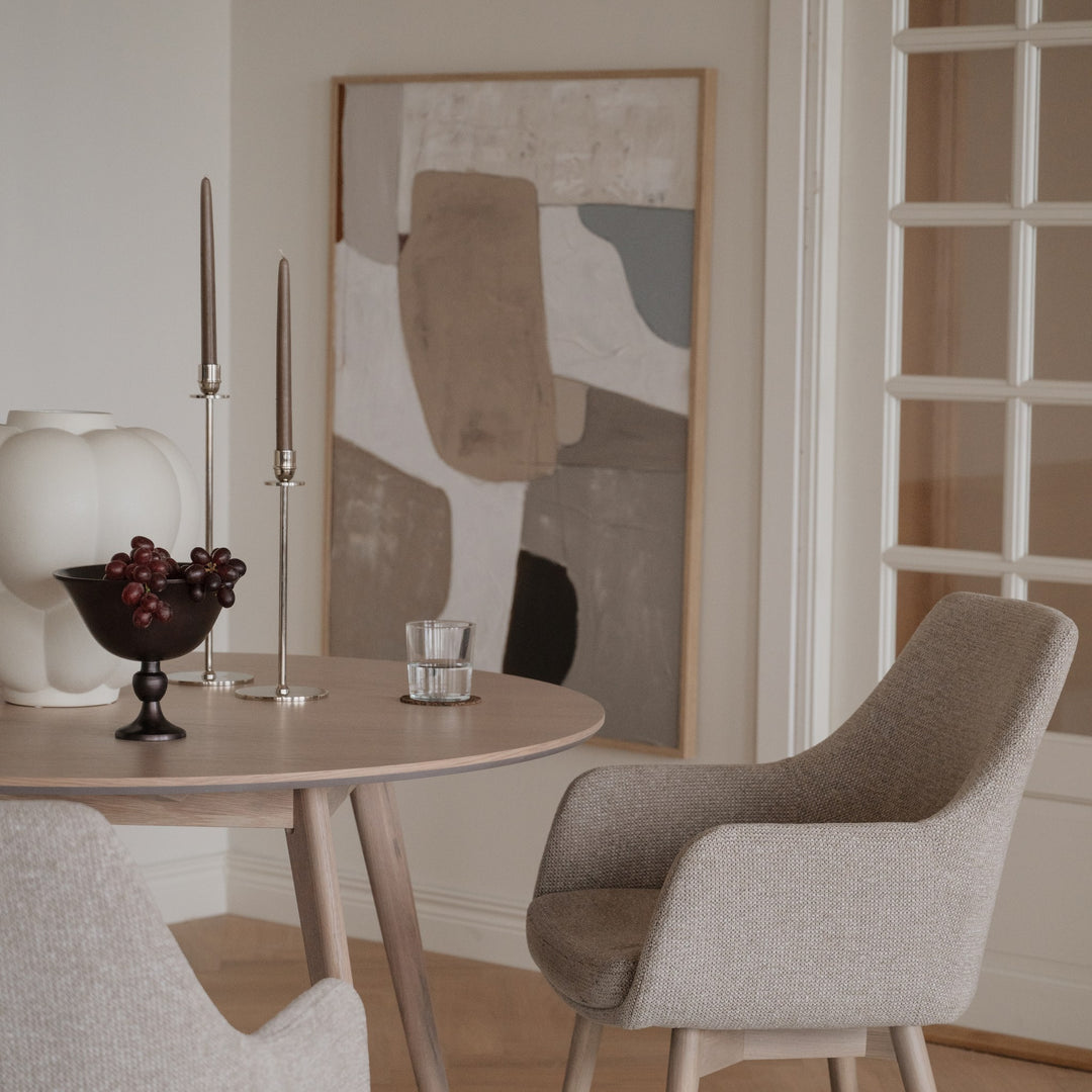 Rowico Denley spisestol i beige stoff ved lyst rundt eikebord med kunst og dekor