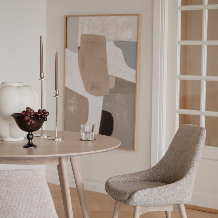 Rowico Denley spisestol i gråbeige stoff ved lyst rundt eikebord med kunst på veggen