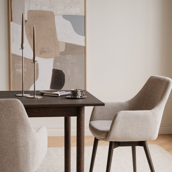 Rowico Denley spisestol i beige stoff med armlener ved mørkt eikebord med kunst på veggen