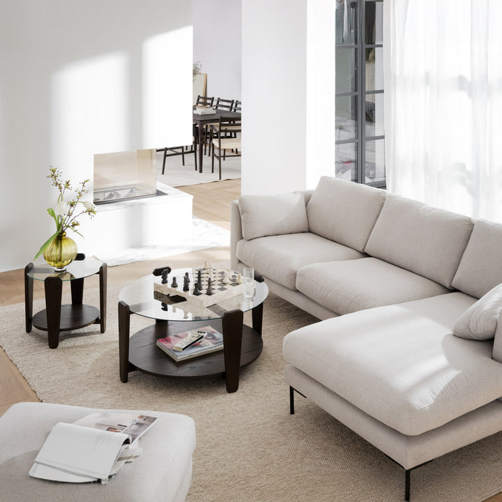 Rowico Arran sofabord i brun eik med glasstopp, ved beige hjørnesofa med sjakkbrett i lyst rom
