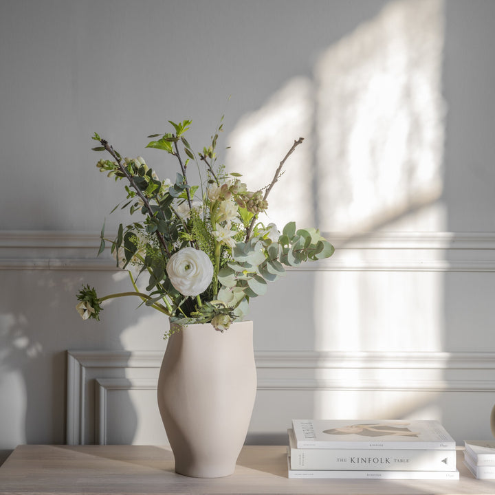Rowico Fred skjenk i hvitpigmentert eik med beige vase og blomsterbukett mot lys panelvegg