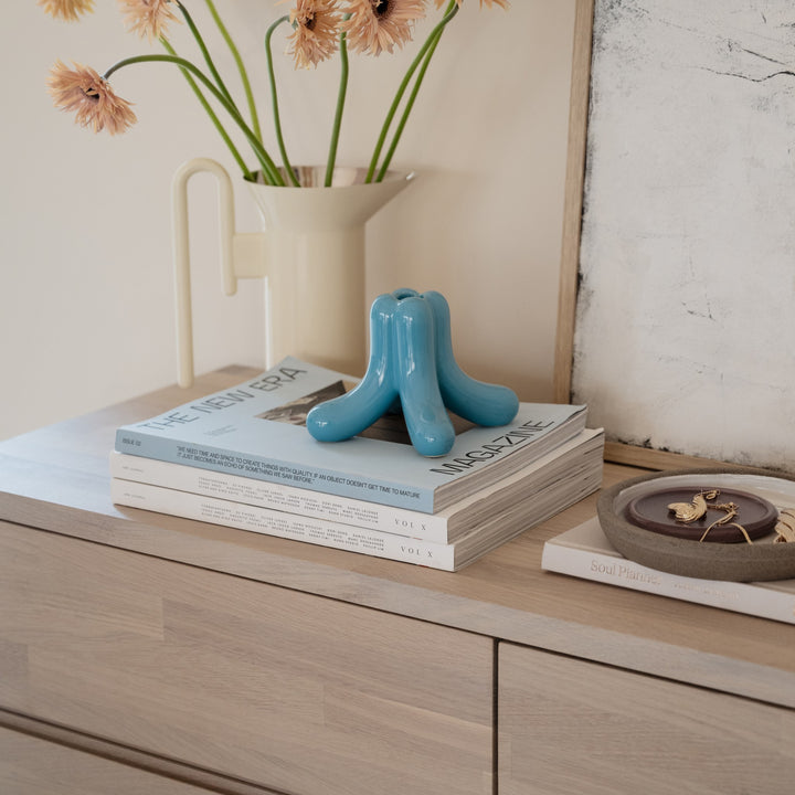 Rowico Cleardale skjenk i hvitpigmentert eik med blå skulptur, bøker og blomster på toppen