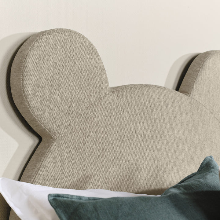 Asleep Teddy sengegavl i beige, nærbilde av bjørneøret med grønn pute og hvitt sengetøy
