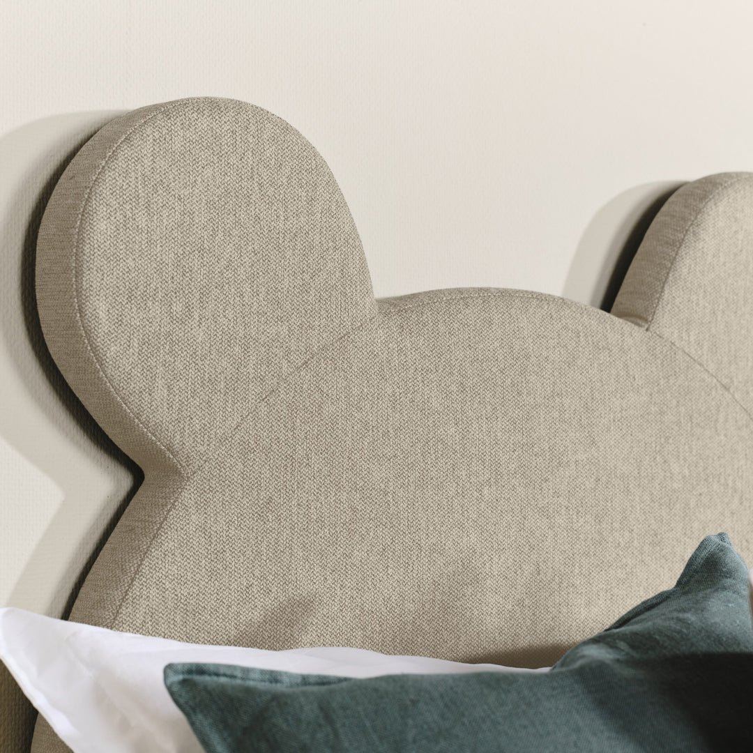 Asleep Teddy rammemadrass i beige, nærbilde av bjørneøret med grønn pute og hvitt sengetøy
