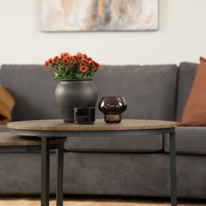 Hastings sofabord, rundt med trelook plate og sorte ben, foran grå sofa med blomster