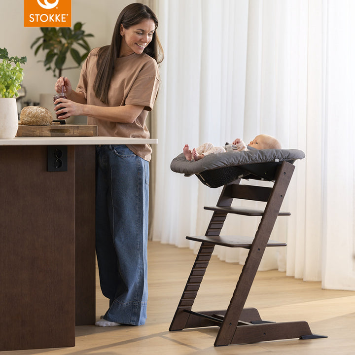 Stokke Tripp Trapp stol i mørkbeiset eik med babysett og spedbarn, mor ved kjøkkenøy