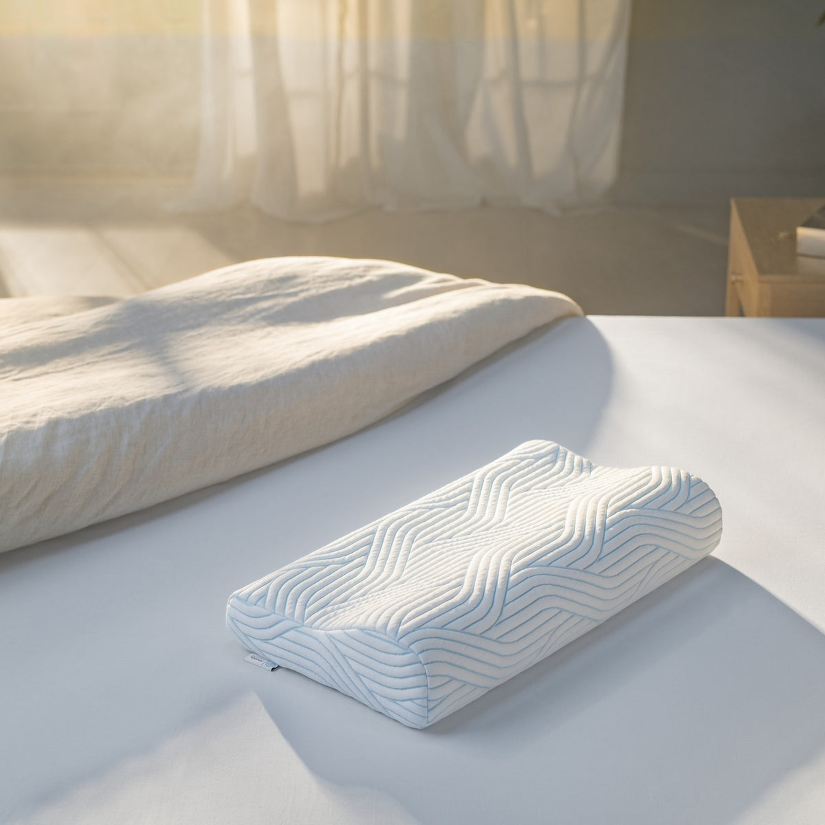 Tempur SmartCool Original hodepute med ergonomisk fasong og blått bølgemønster på lys seng