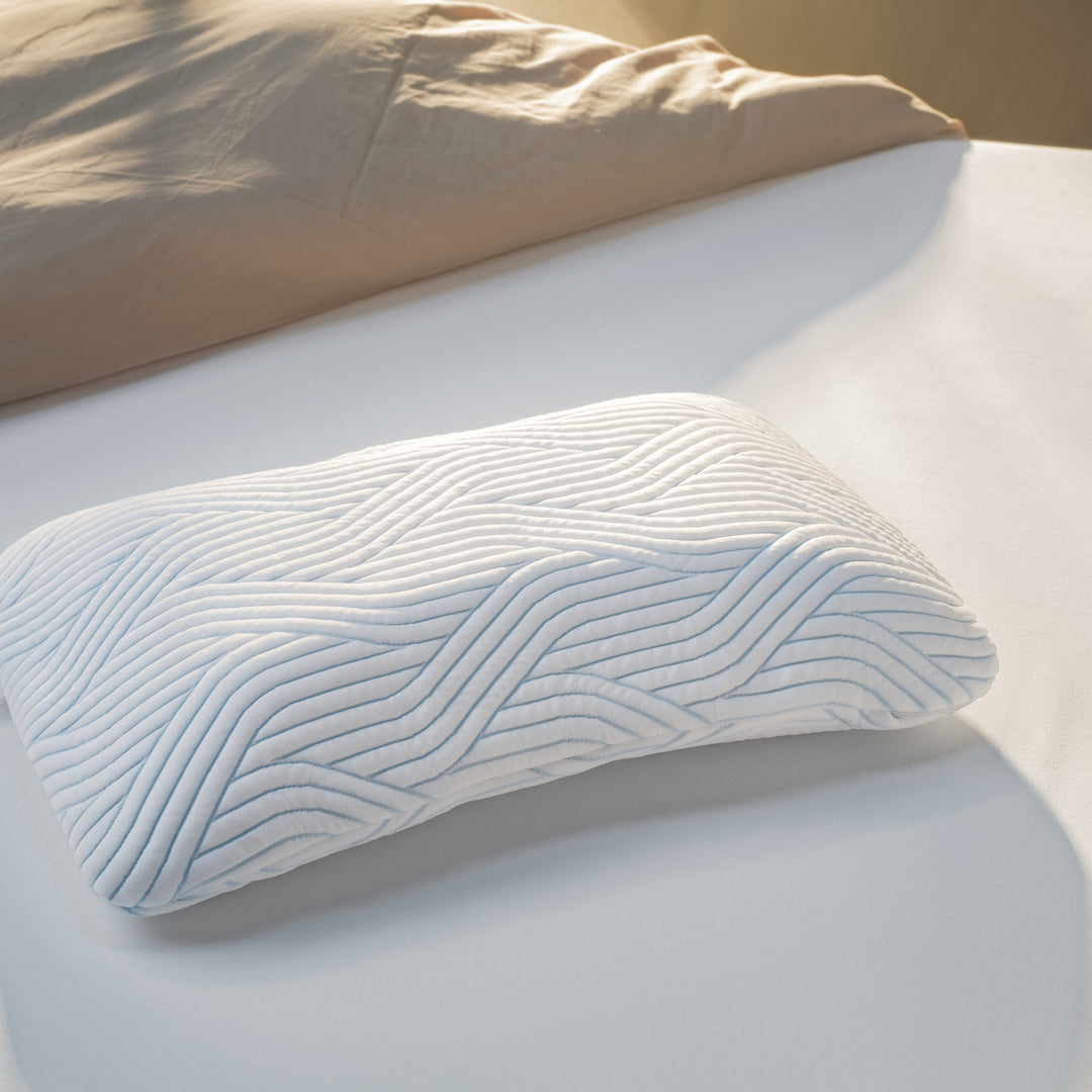 Tempur SmartCool Symphony hodepute med blått bølgemønster på lys seng med beige sengetøy