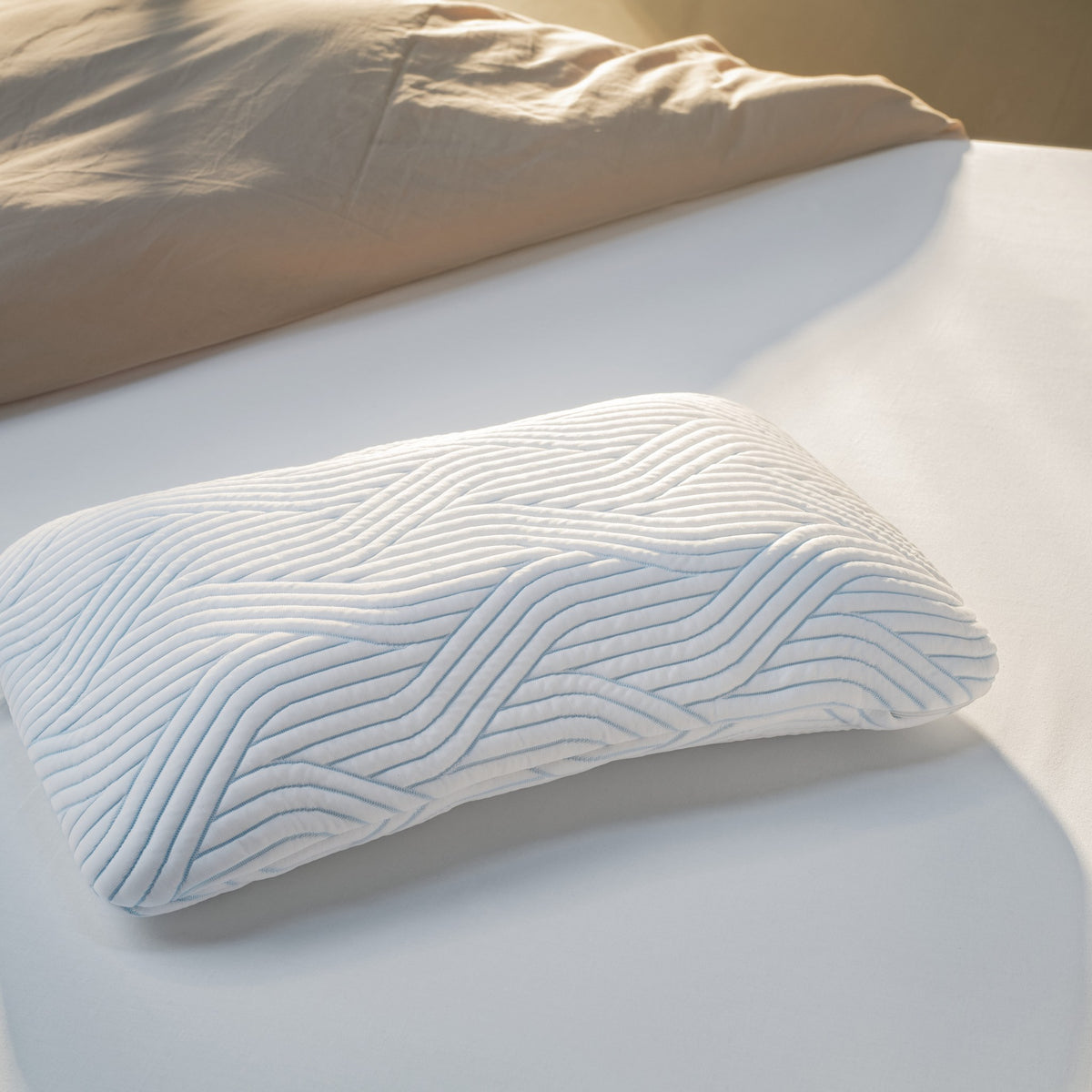 Tempur SmartCool Symphony hodepute med blått bølgemønster på lys seng med beige sengetøy