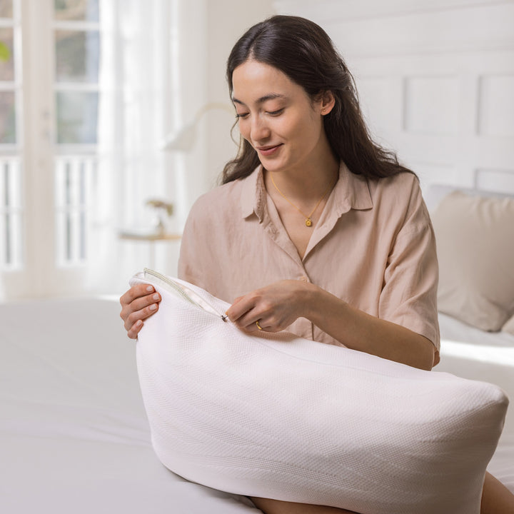 Tempur Comfort PureClean hodepute, kvinne åpner det avtagbare glidelåstrekket i lyst soverom