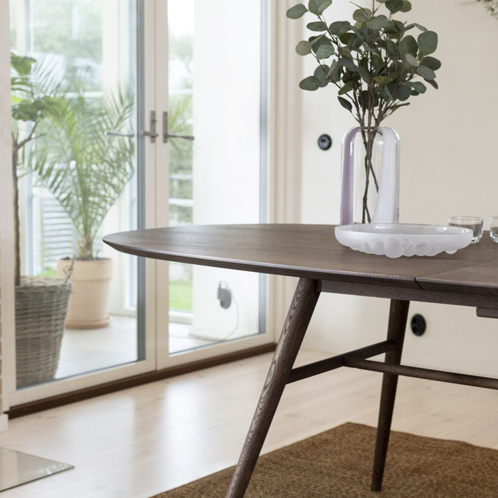 Joel spisebord i mørk eik ved terrassedør, med vase og planter i lyst rom