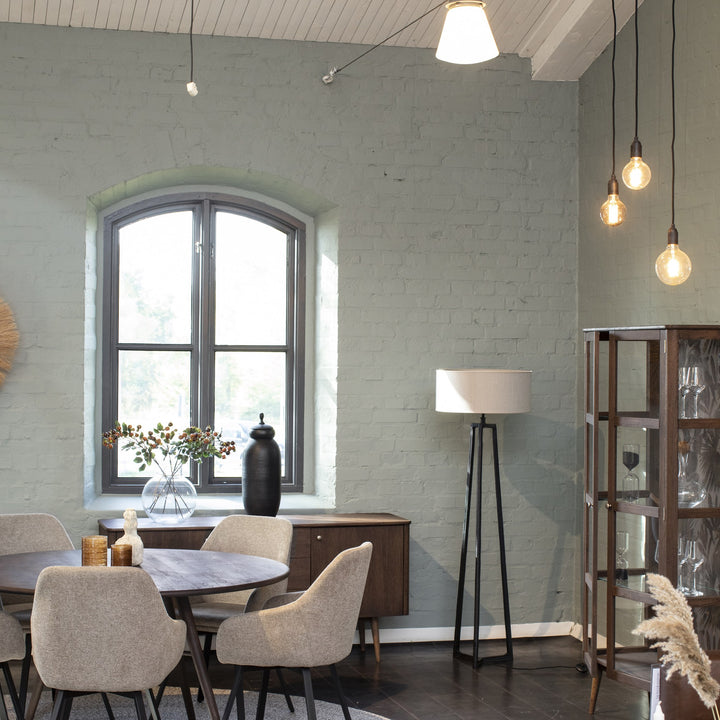 Løderup spisebord i mørk eik med beige stoler i industrielt rom med buevindu og grå teglvegg