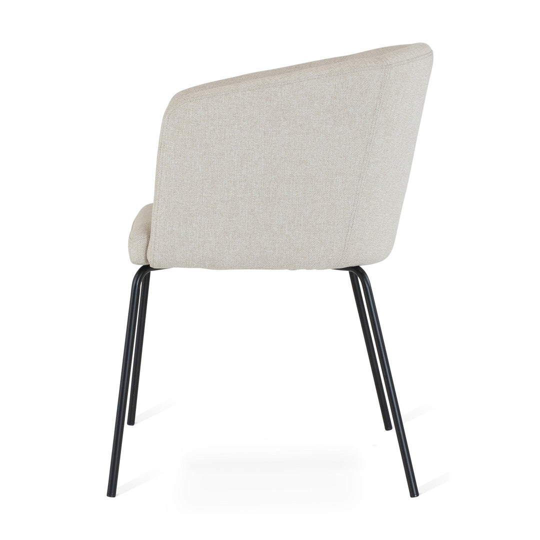 Fab spisestol i beige stoff med buet rygg og sorte ben, sett fra siden mot hvit bakgrunn
