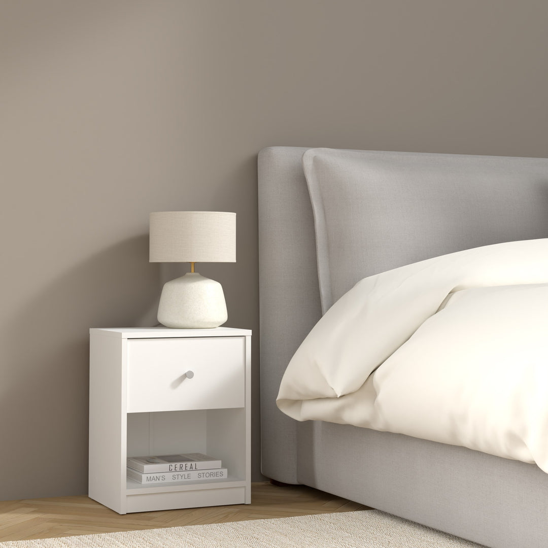 May nattbord i hvitt med skuff og åpen hylle, med lampe ved grå seng i soverom