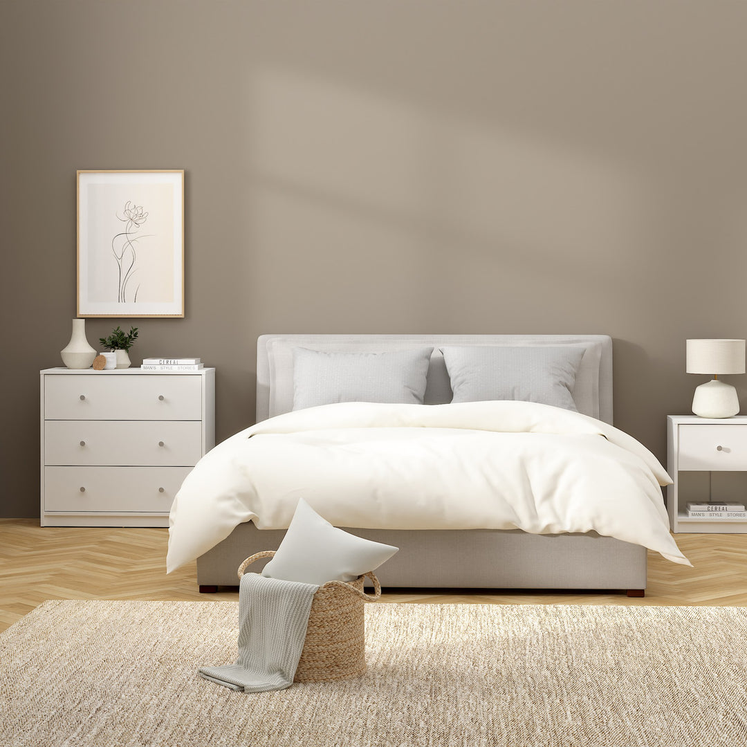 May kommode i hvit på soverom med dobbeltseng, bordlampe og innrammet bilde