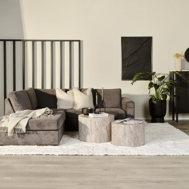 Oslo hjørnesofa i mørk grå velur med venstrevendt sjeselong, hvitt ryeteppe og runde trestubbebord