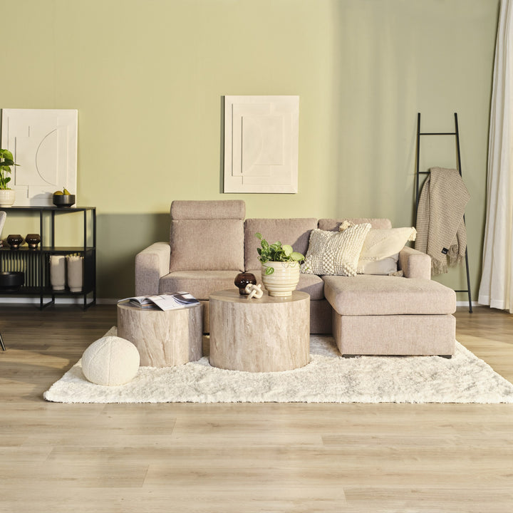 Oslo hjørnesofa i beige stoff med høyrevendt sjeselong mot grønn vegg, trestubbebord og hvitt teppe
