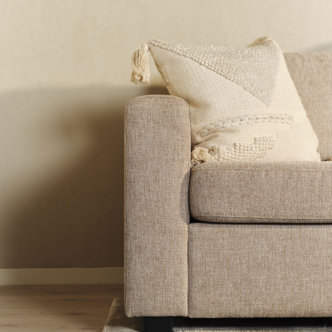 Oslo hjørnesofa i beige, nærbilde av armlene med kremhvit pute mot beige vegg