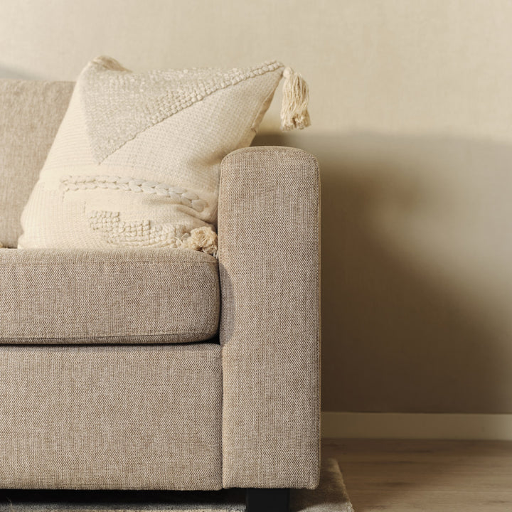 Oslo hjørnesofa i beige, nærbilde av armlene og kremhvit pute med dusker