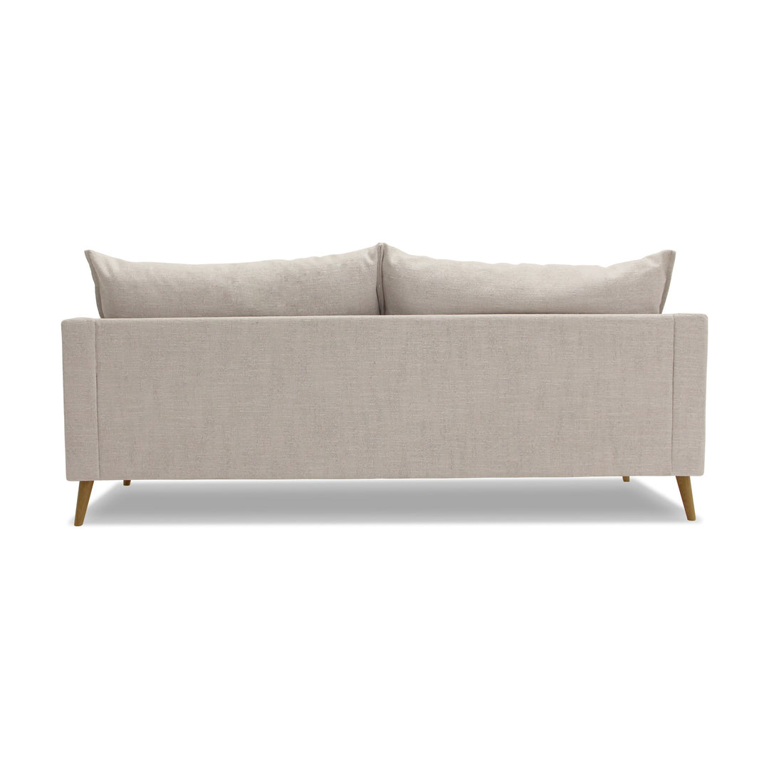Justin sofa i lys beige stoff med løse ryggputer og treben, sett bakfra.