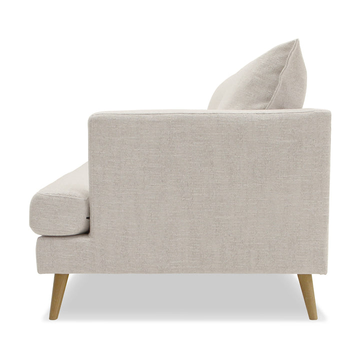 Justin sofa i lys beige stoff med treben, sett fra siden.