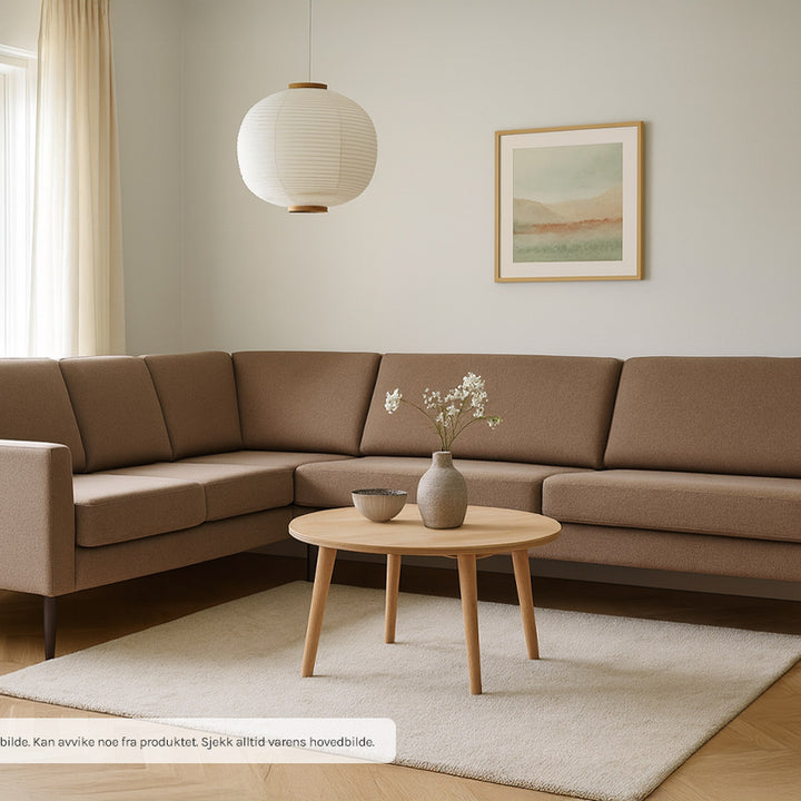 Pescara sofa i brun stoff med høyrevendt hjørne, rundt eikebord, rispapirlampe og beige teppe
