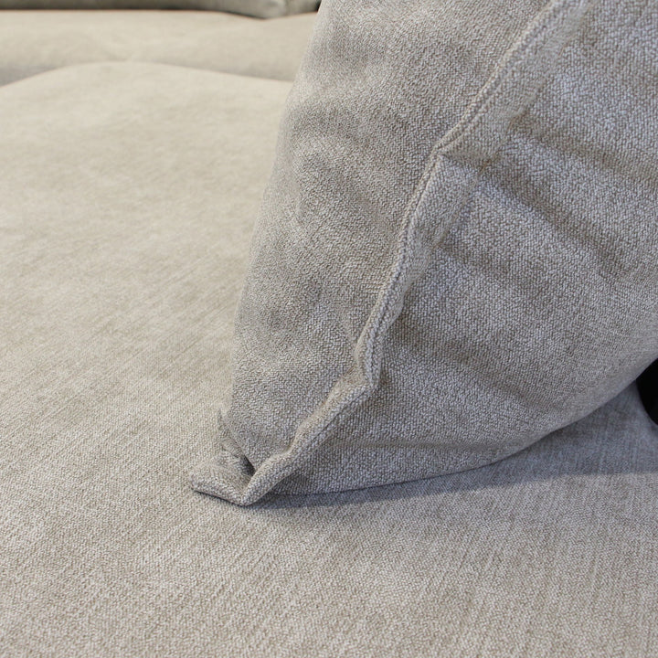 Justin hjørnesofa i beige stoff, nærbilde av pute mot lyst setetrekk