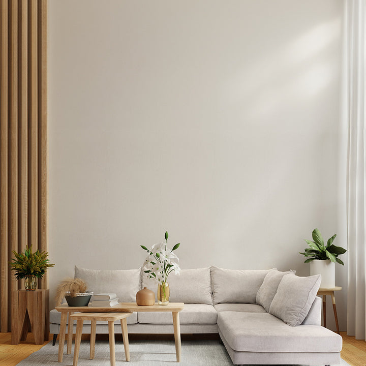 Justin hjørnesofa i beige stoff i lys stue med trepanel, sofabord, planter og hvite liljer