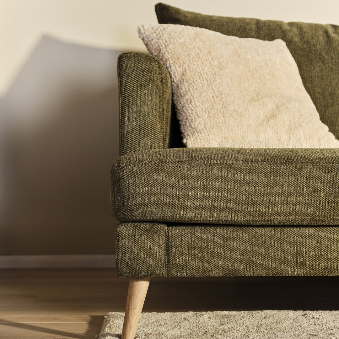 Justin hjørnesofa i olivengrønn stoff med hvit bouclépute, treben og beige vegg