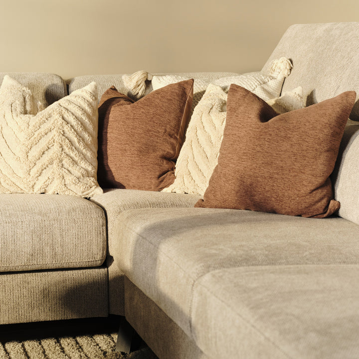 Billund hjørnesofa i beige stoff med brune og kremhvite puter, nærbilde av rygg og sete