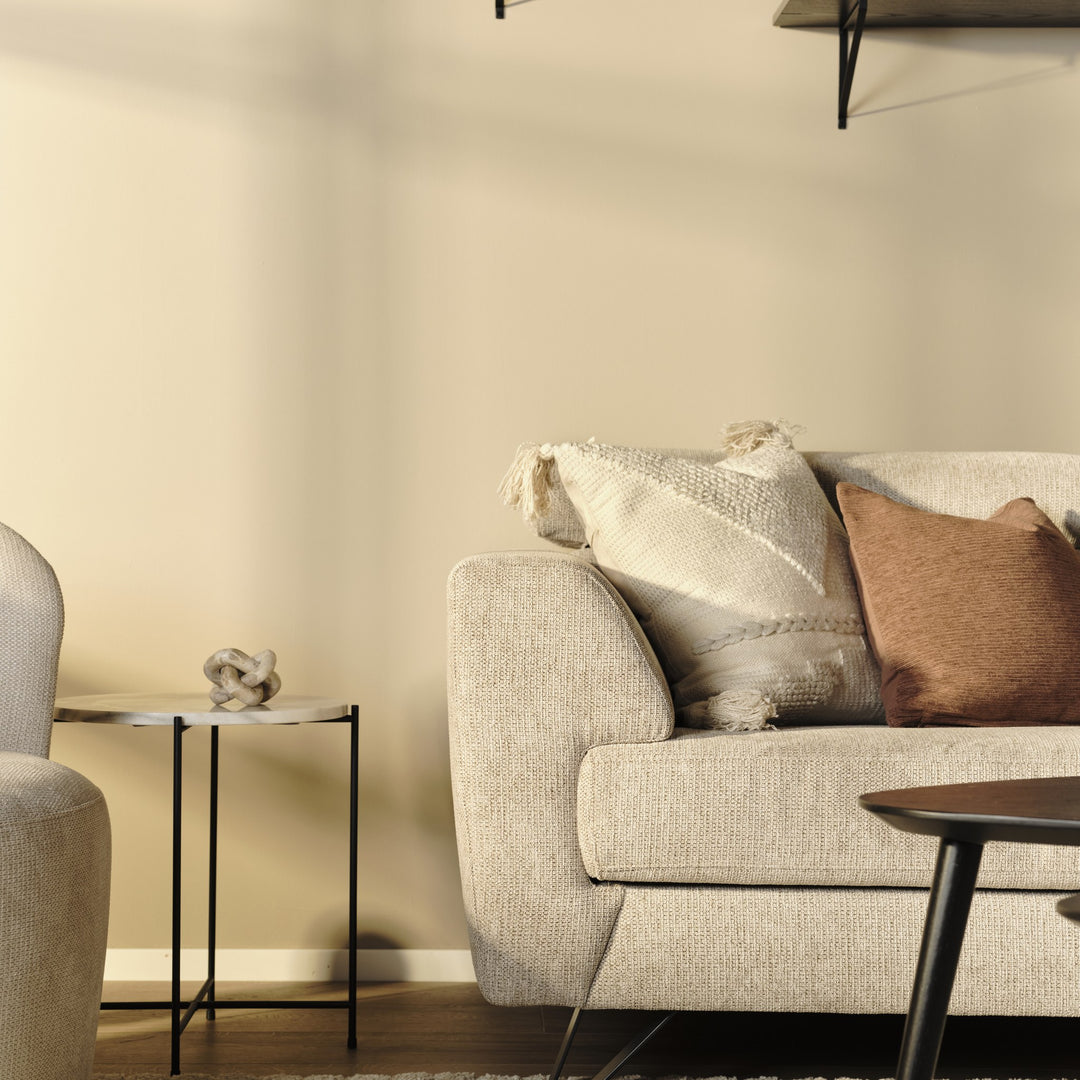 Billund hjørnesofa i beige stoff med kremhvit og terrakotta pute, ved sidebord og sofabord