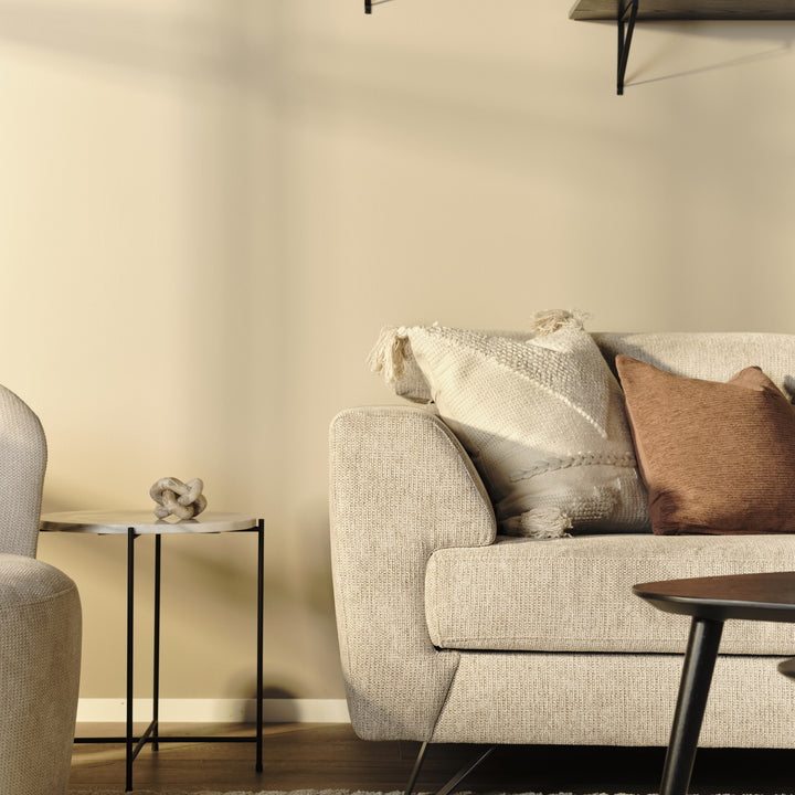 Billund hjørnesofa i beige stoff med kremhvit og terrakotta pute, ved sidebord og sofabord