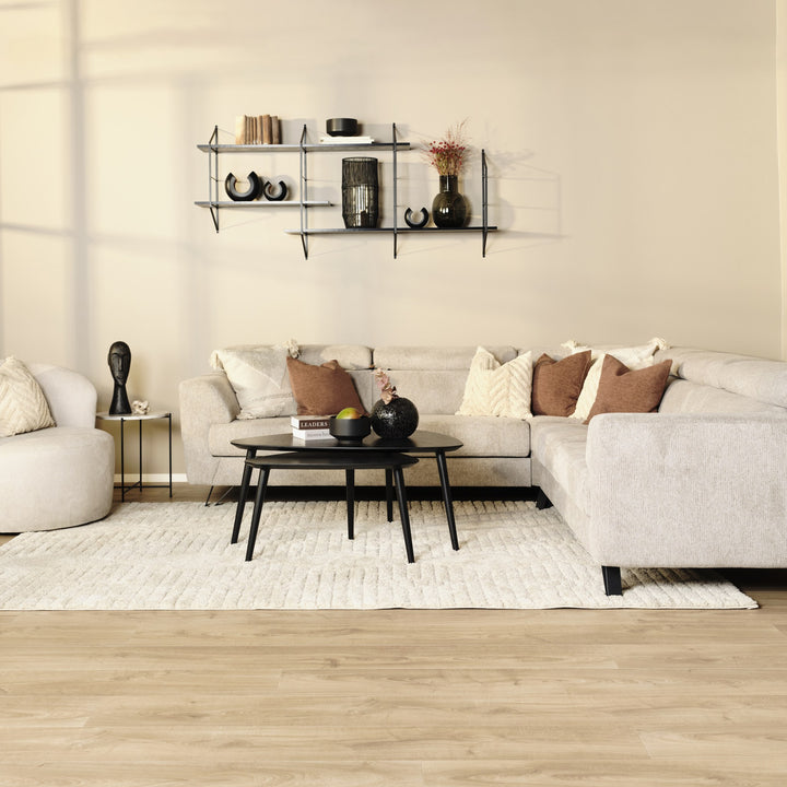 Billund hjørnesofa i beige stoff med sort sofabord, vegghylle og lyst ryeteppe