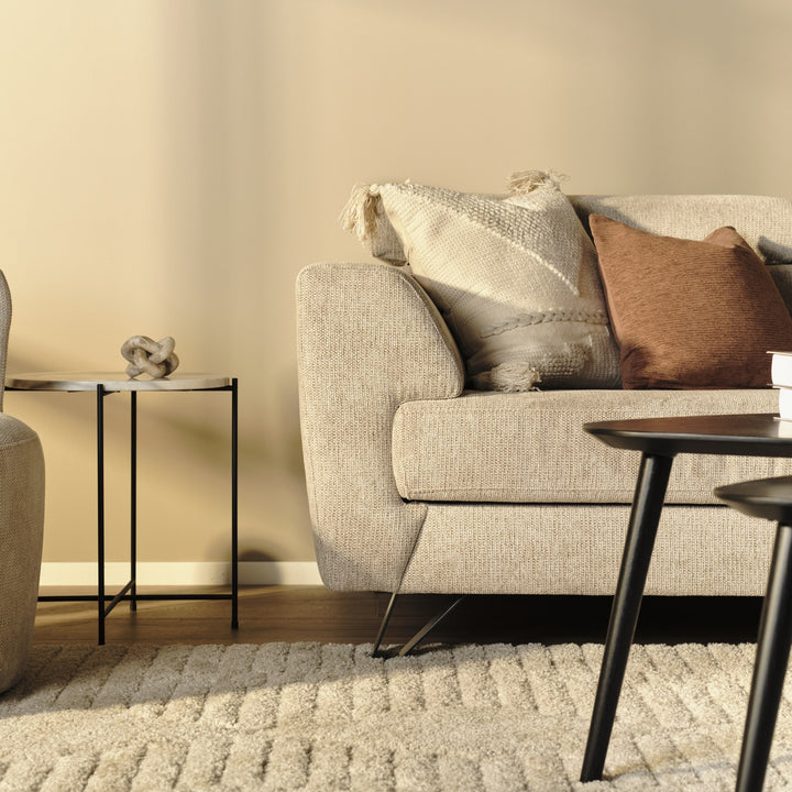 Billund hjørnesofa i beige stoff, nærbilde av armlene og pute ved sidebord