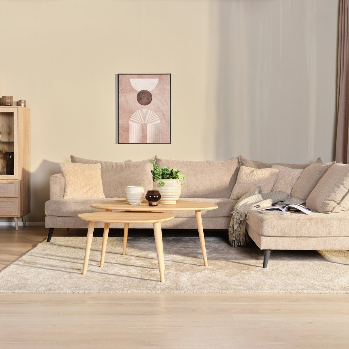 Justin hjørnesofa i beige stoff, høyrevendt sjeselong, runde eikebord og rosa plakat