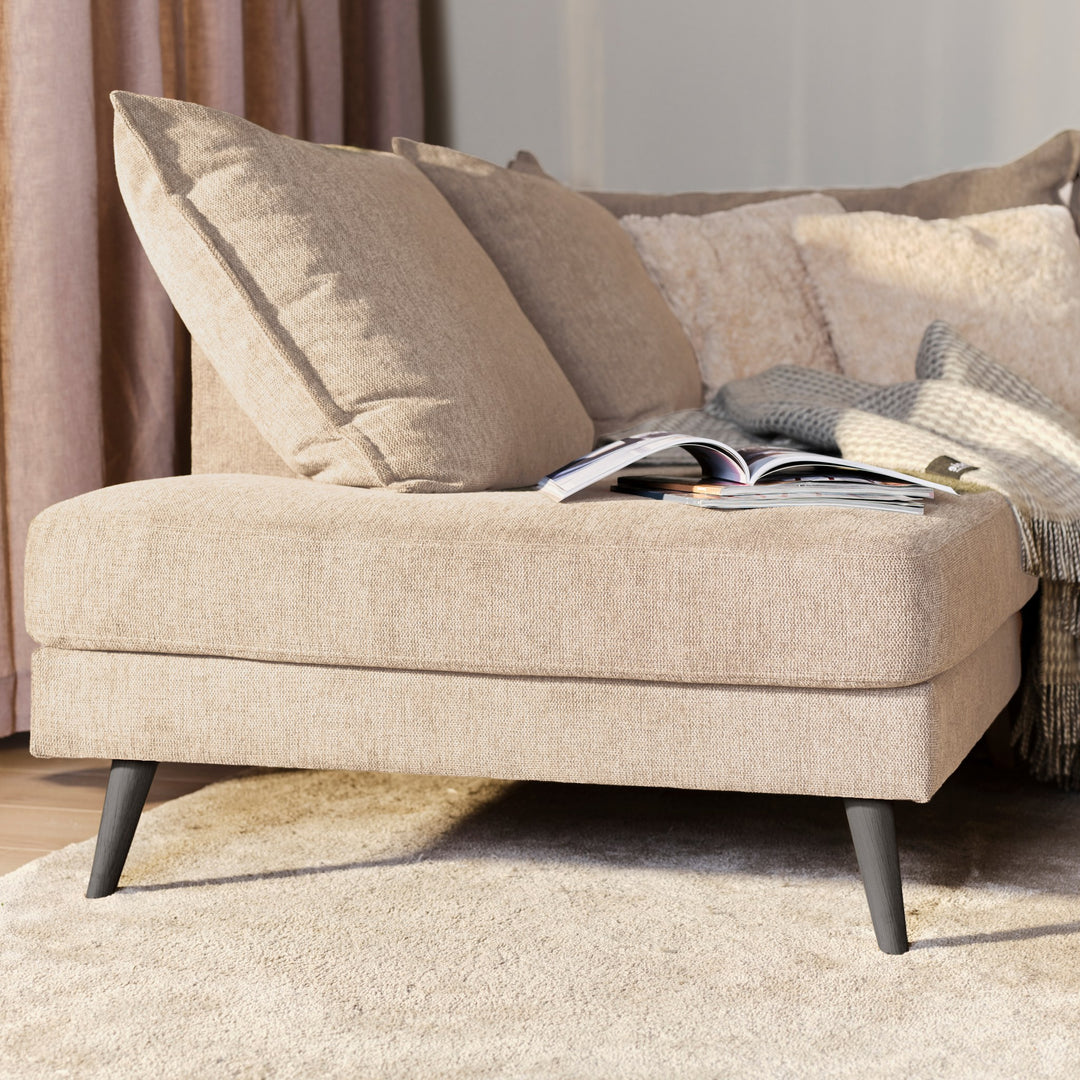 Justin hjørnesofa i beige stoff med puter, pledd og oppslått magasin