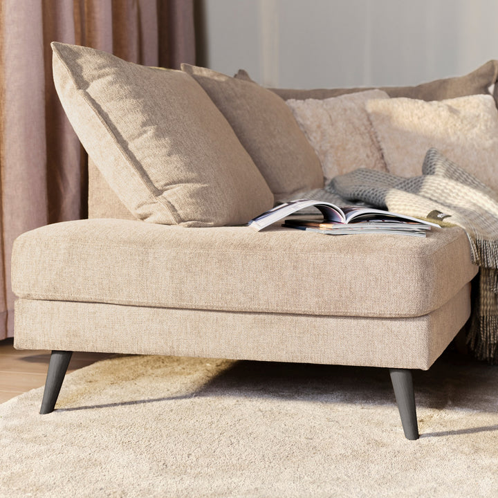 Justin hjørnesofa i beige stoff med puter, pledd og oppslått magasin