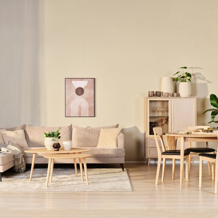 Justin hjørnesofa i beige stoff i lys stue med spisebord, trekommode og runde sofabord