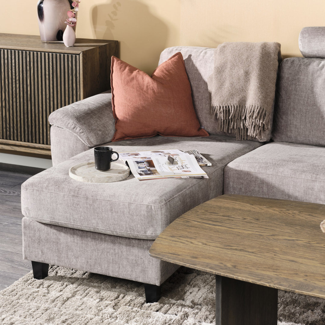 Solution hjørnesofa i taupe stoff, nærbilde av sjeselong med terrakottapute og pledd