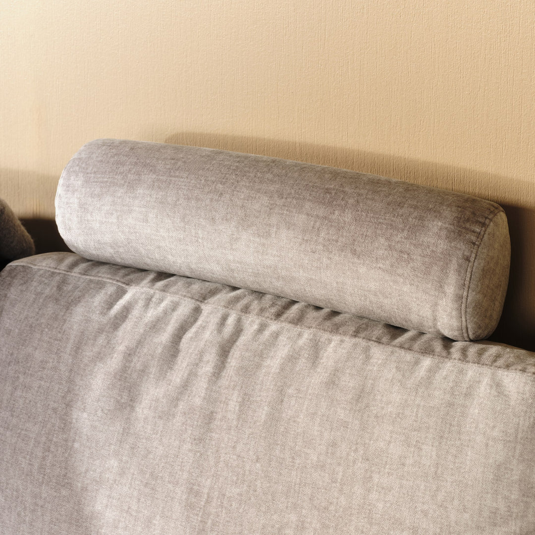 Solution hjørnesofa, nærbilde av avlang nakkepute i greige stoff mot gul vegg