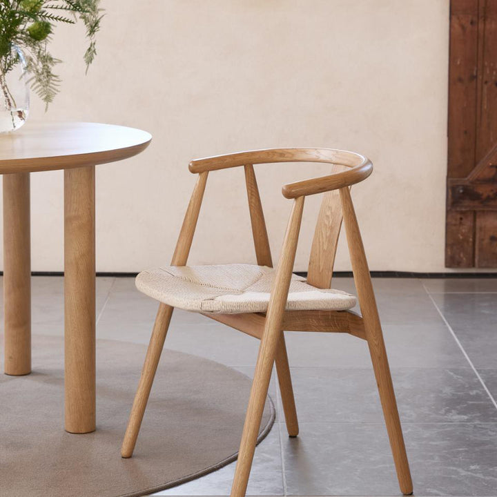 Relate spisestol i natur eik med flettet naturtau-sete, ved rundt eikebord mot beige vegg