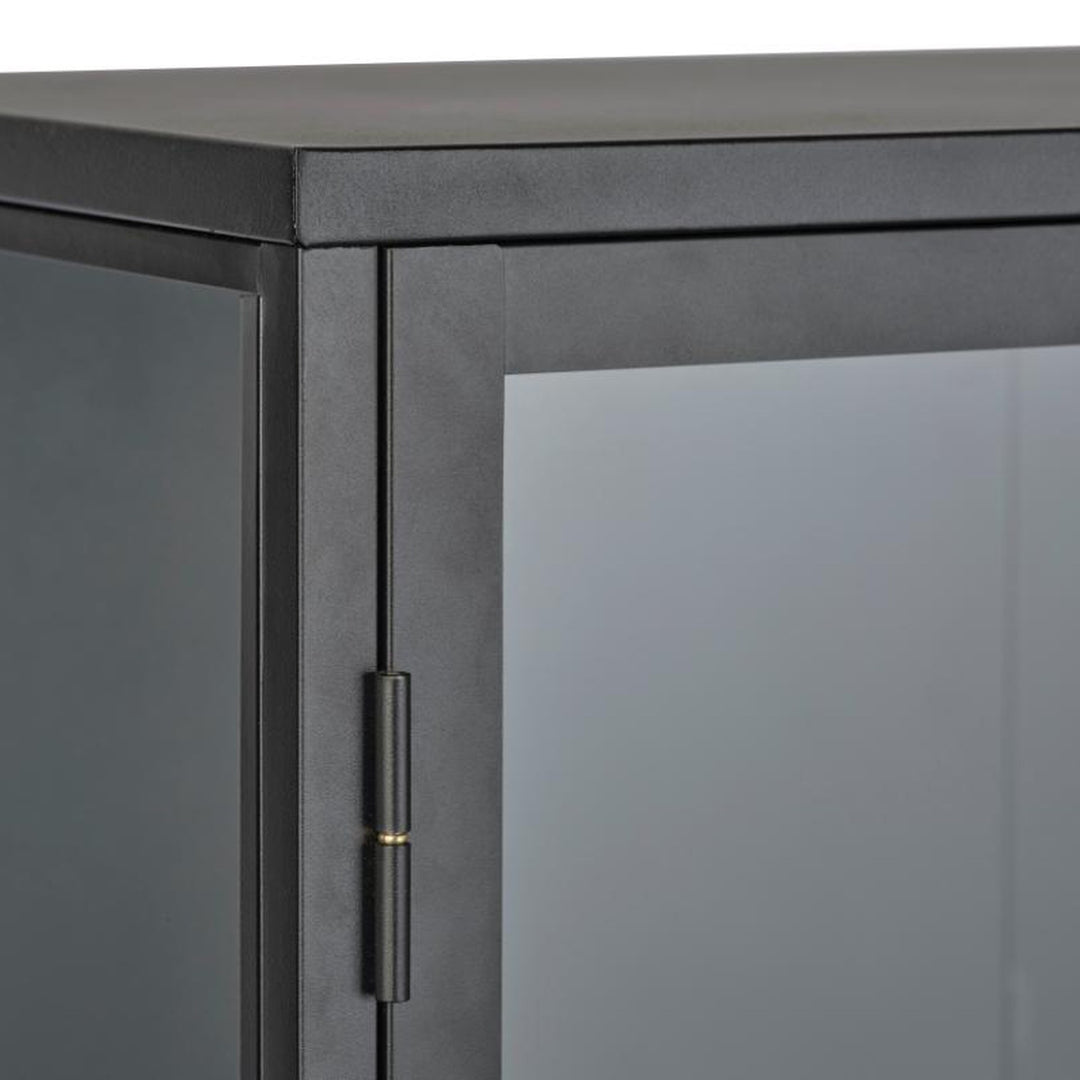 Carmel skap i sort, detalj av øvre hjørne med metallramme, glass og hengsel med messingdetalj